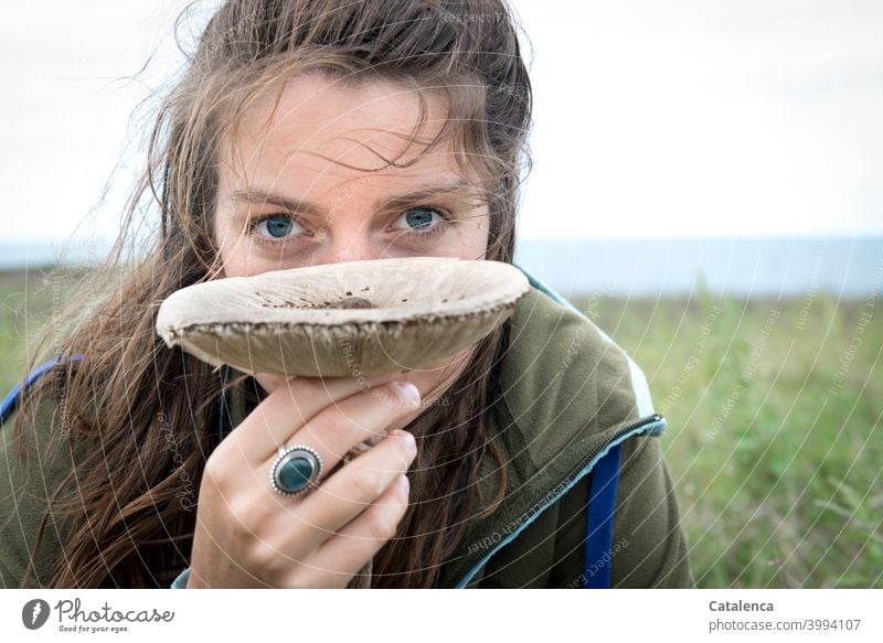 Junge Frau hält einen  großen Lamellenpilz und schaut in die Kamera Natur Sommer Tageslicht Himmel gedeihen wachsen Pilz Wiese Grashalme Pflanze brünett Ring