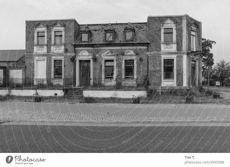 ein altes kaputtes Haus an der Straße in Brandenburg s/w b/w Fenster Schwarzweißfoto ruhig Einsamkeit Architektur b&w Außenaufnahme dunkel Ruine Dorf Gebäude