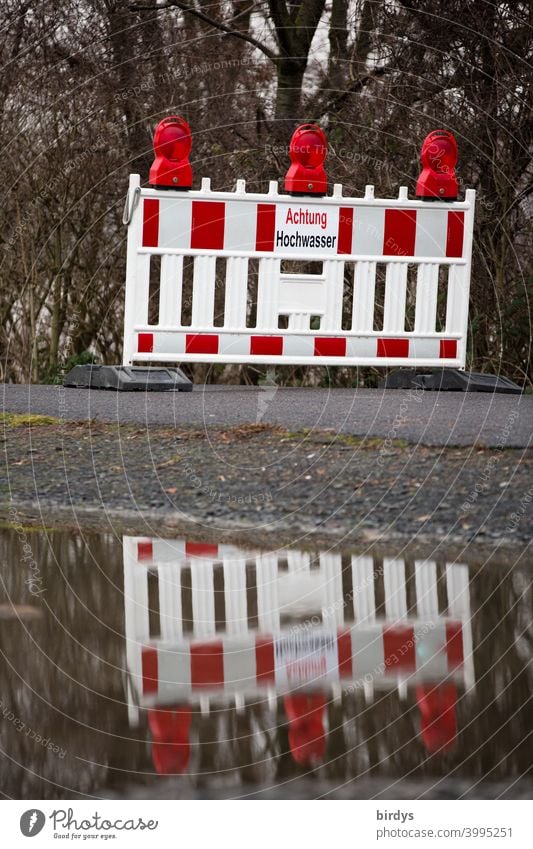 amtliche Absperrung eines Weges wegen Hochwasser. Leuchtbake mit Warnschild spiegelt sich im Wasser Überflutung Gefahr Spiegelung Sicherheit Warnhinweis