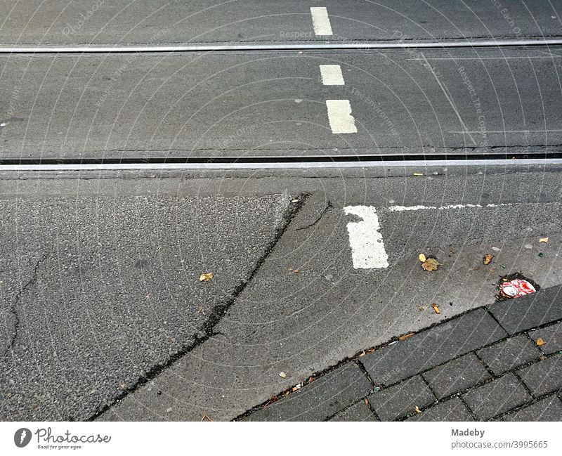 Alter grauer Asphalt mit Straßenbahnschienen und weißer Markierung eines Fußgängerüberweg in Köln am Rhein in Nordrhein-Westfalen Fahrbahn Schiene Verkehr