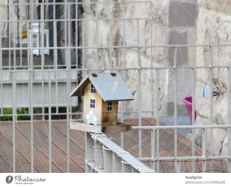 Vogelhäuschen auf einem Balkon Futterhäuschen füttern Außenaufnahme Menschenleer Tag Naturschutz Hilfe Balkongitter Balkonbrüstung Häuschen Futterplatz