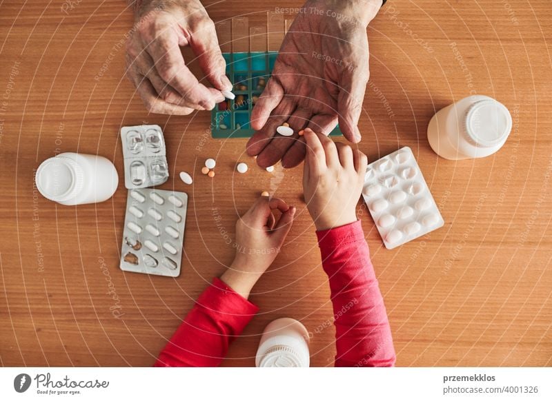 Enkelkind hilft Großvater, Medikamente in Pillendose zu organisieren. Senior Mann nimmt Pillen aus Box Tablette Krankheit Spender geduldig Verschreibung