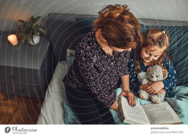 Mutter lesen Buch ihre Tochter im Bett vor dem Schlafengehen. Gutenachtgeschichten für Kind Nacht Schlafenszeit Familie heimwärts Literatur Frau Schlafzimmer