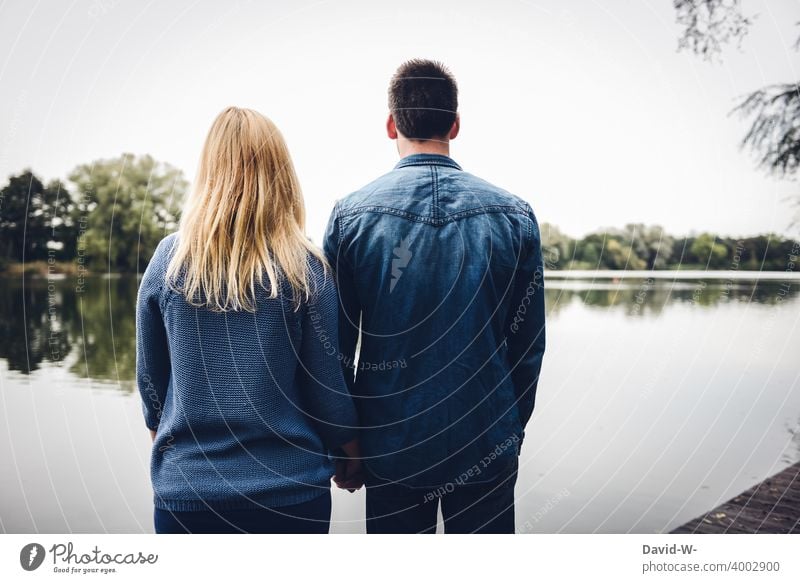 Mann und Frau stehen gemeinsam am See und blicken in die Ferne zusammen Pärchen Liebe zusammenhalt Blicken Natur Zusammenhalt Gemeinschaft Rückansicht