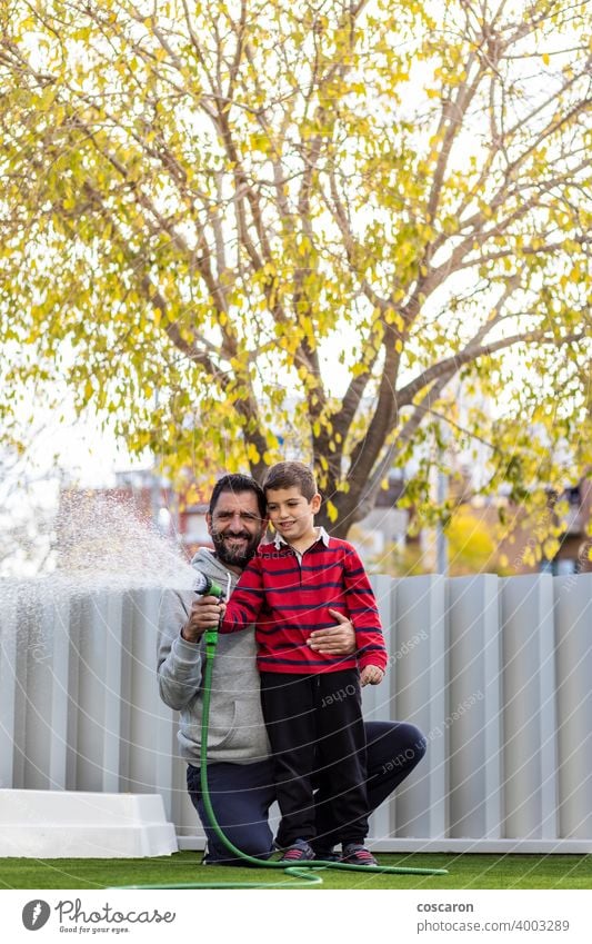 Vater und Sohn bewässern das Gras auf ihrem Haus aktiv Aktivität Baby Hinterhof Junge Kind Kindheit Papa Tropfen Familie Spaß Spiel Garten Gartenarbeit Glück