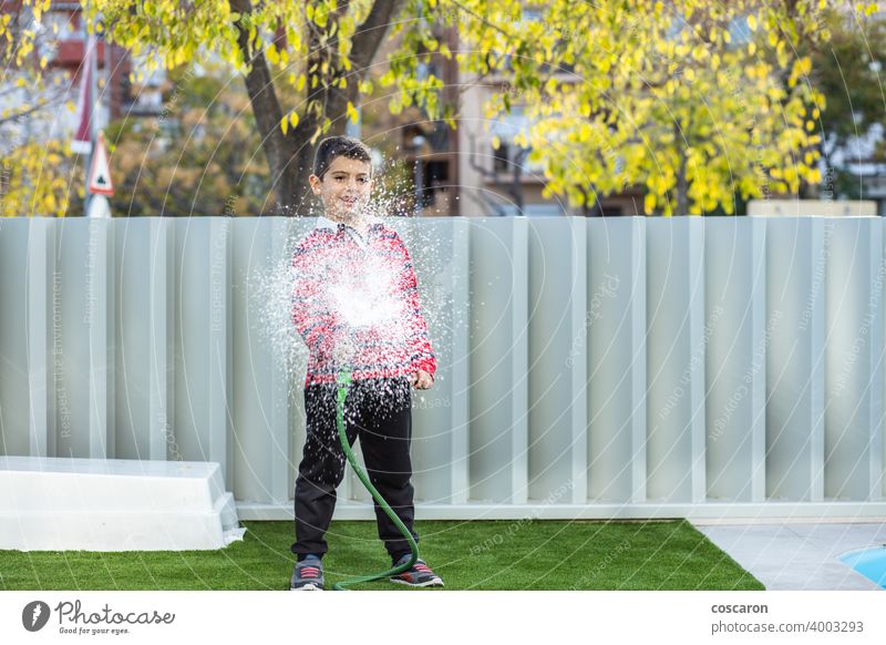 Kleiner Junge bewässert das Gras im Garten Aktion Aktivität Kind Kindheit Kinder Tropfen genießen Familie Springbrunnen frisch Spaß Gartenarbeit grün