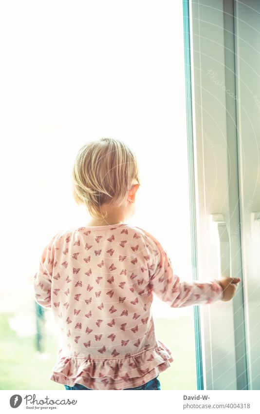 Kind schaut aus dem Fenster sehnsüchtig blick nach draussen Quarantäne abgeschirmt traurig Gedanken nachdenklich Corona coronavirus psyche Kindheit