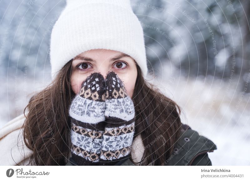 Junges Mädchen, Frau in gestrickten Handschuhen fühlt sich kalt. Walking in schönen Winterwald unter Bäumen, Tannen, mit Schnee bedeckt. Prächtige Natur. Modisches Bild, Kleidung, Parka, Hut, Blue Jeans