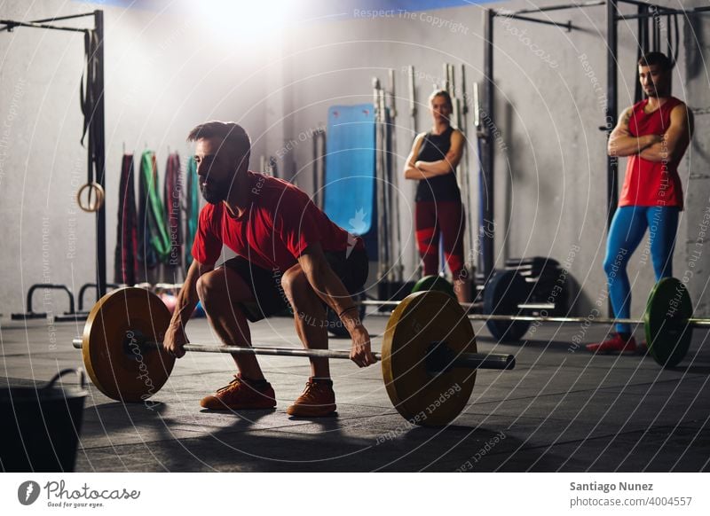 Mann hockt und hebt eine Langhantel. Crossfit Funktionstraining Fitnessstudio Gesundheit Sport Training Übung Lifestyle passen Erwachsener Vitalität