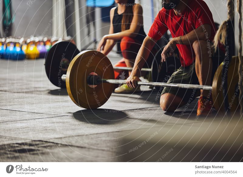 Menschen, die vor Hanteln knien. Crossfit Funktionstraining Fitnessstudio Gesundheit Sport Training Übung Lifestyle Sportbekleidung Kunstturnen Gerät vereinzelt