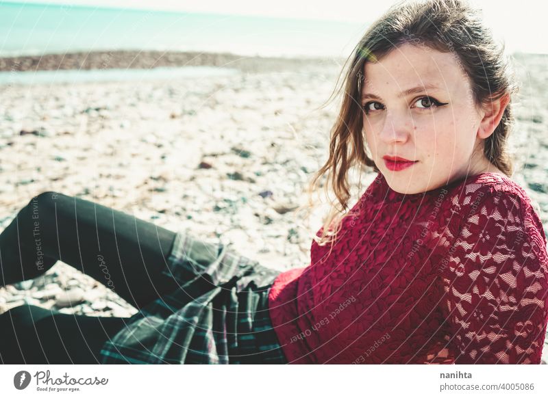 Junge und trendige Frau in einem sonnigen Tag sitzen am Strand trendy attraktiv Spitze Model Sand Hintergrundbeleuchtung rot blond Sonne sexy jung Jugend