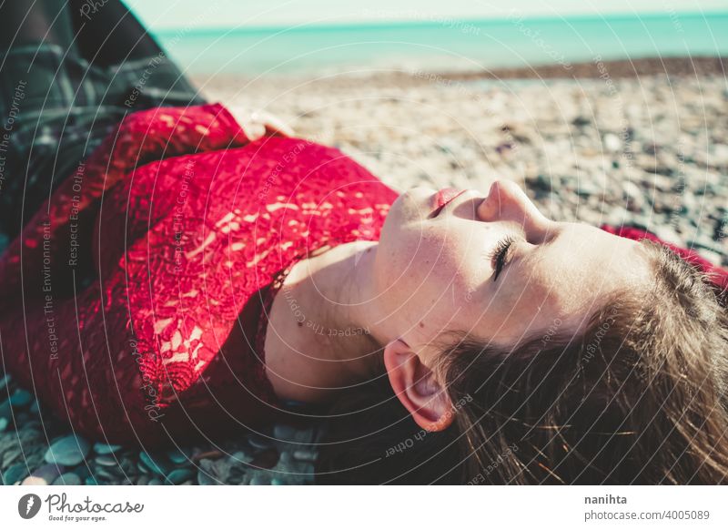 Junge und trendige Frau in einem sonnigen Tag sitzen am Strand trendy attraktiv Spitze Model Sand Hintergrundbeleuchtung rot blond Sonne sexy jung Jugend