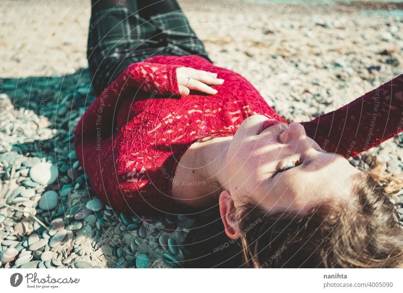 Junge und trendige Frau in einem sonnigen Tag sitzen am Strand trendy attraktiv Spitze Model Sand Hintergrundbeleuchtung rot blond Sonne sexy jung Jugend