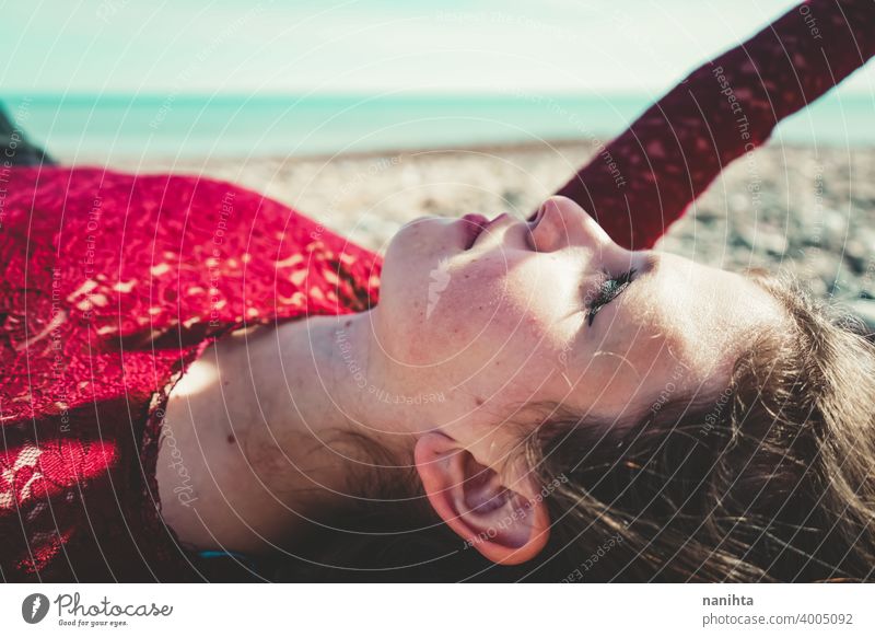 Junge und trendige Frau in einem sonnigen Tag sitzen am Strand trendy attraktiv Spitze Model Sand Hintergrundbeleuchtung rot blond Sonne sexy jung Jugend