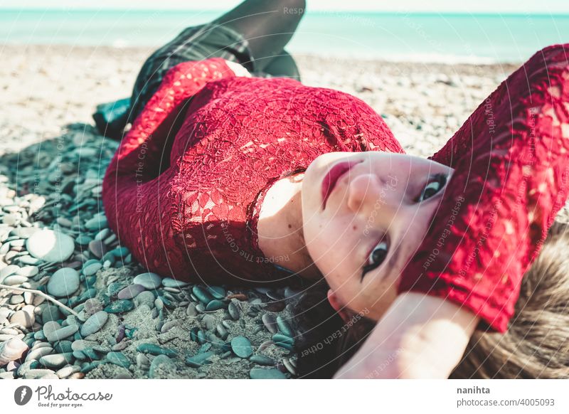 Junge und trendige Frau in einem sonnigen Tag sitzen am Strand trendy attraktiv Spitze Model Sand Hintergrundbeleuchtung rot blond Sonne sexy jung Jugend