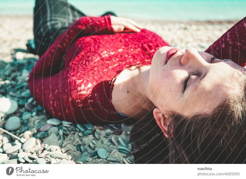 Junge und trendige Frau in einem sonnigen Tag sitzen am Strand trendy attraktiv Spitze Model Sand Hintergrundbeleuchtung rot blond Sonne sexy jung Jugend