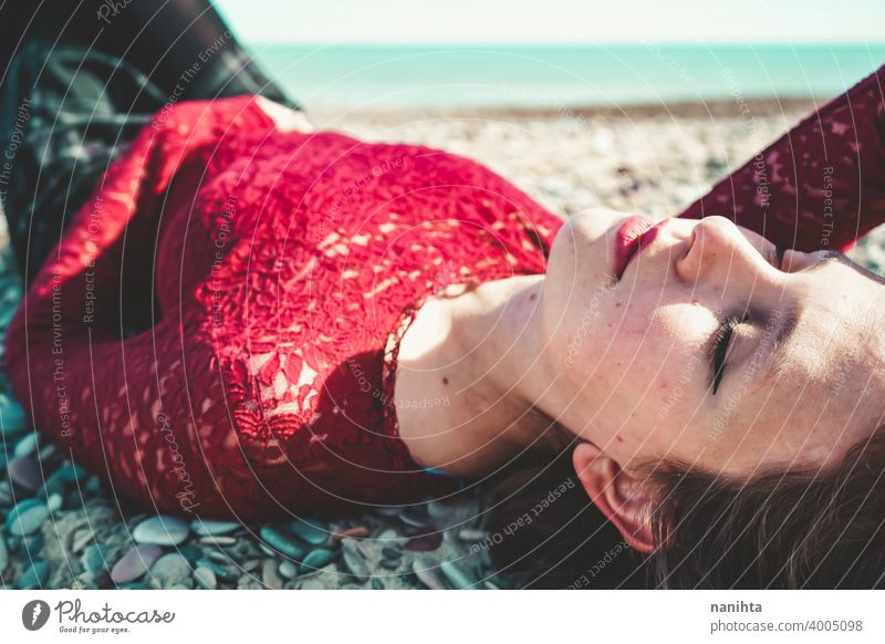 Junge und trendige Frau in einem sonnigen Tag sitzen am Strand trendy attraktiv Spitze Model Sand Hintergrundbeleuchtung rot blond Sonne sexy jung Jugend