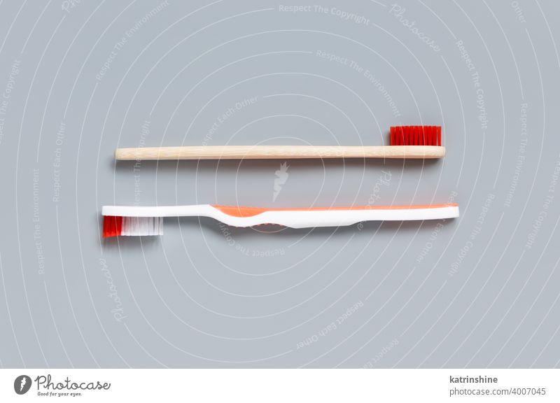 Kunststoff- und Bambuszahnbürsten auf grauem Hintergrund Zahnbürste Draufsicht hölzern dental Toilettenartikel mündlich natürlich Hygiene niemand alternativ