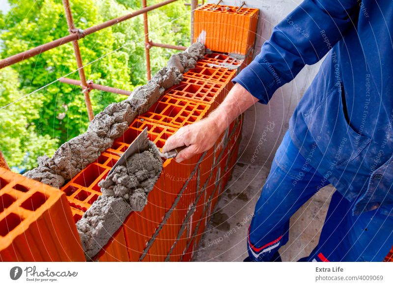 Bauherr verwendet Spachtel zum Ansetzen von Mörtel über rotem Backstein Genauigkeit genau bewerben Klotz Baustein Maurer Maurerarbeiten Mauerwerk Baustelle