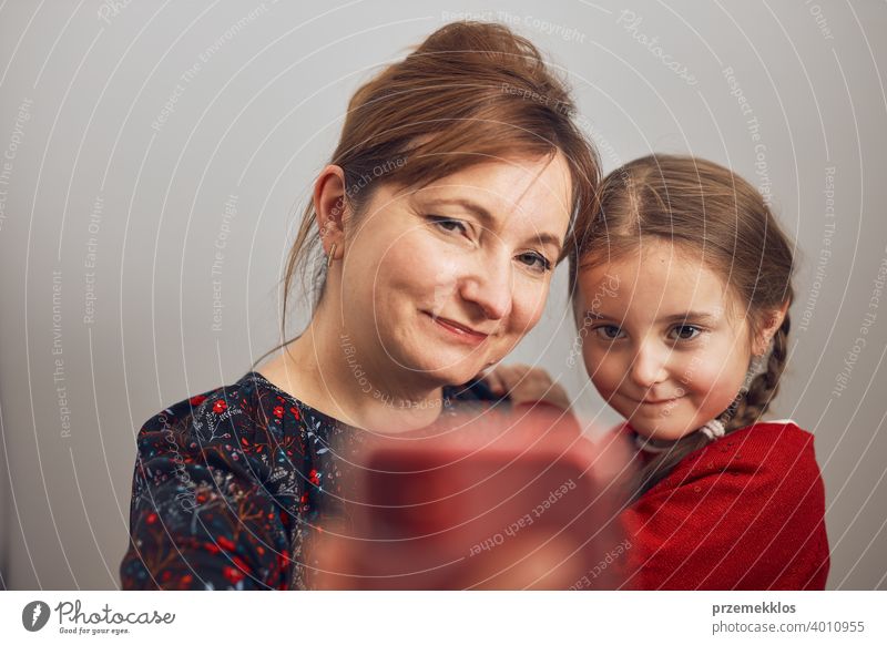 Mutter mit ihrer kleinen Tochter machen Videoanruf mit Handy. Frau und kleines Mädchen im Gespräch mit Verwandten. Fröhliche Familie mit Spaß nehmen selfie Foto mit Smartphone