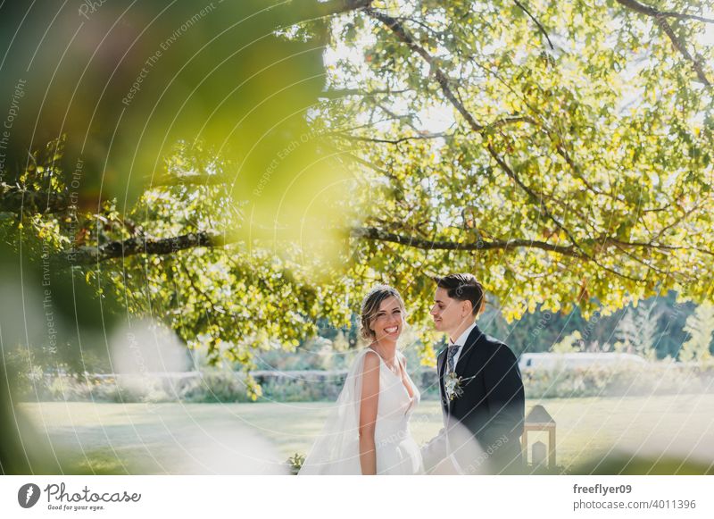 Junges Paar schaut sich an ihrem Hochzeitstag an Heirat Engagement Braut Menschen jung attraktiv Textfreiraum striegeln Baum Natur Außenseite Sonnenlicht Sommer