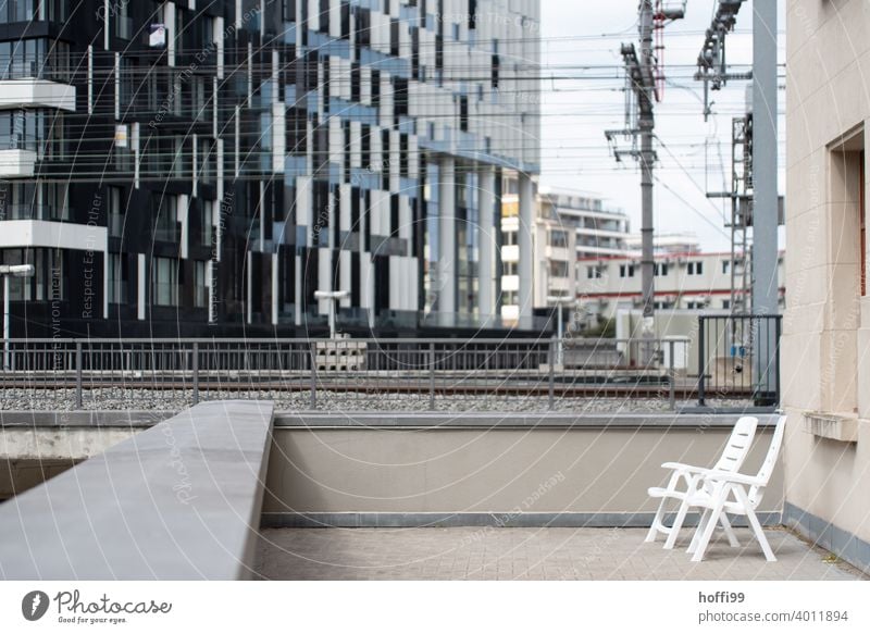 urbane Zweisamkeit am Gleis Balkon Gartenstühle Bahngleise Eisenbahn Tristesse Gleise Vereinsamung Schienenverkehr Bahnhof Hochhaus Hochhausfassade laut Stress