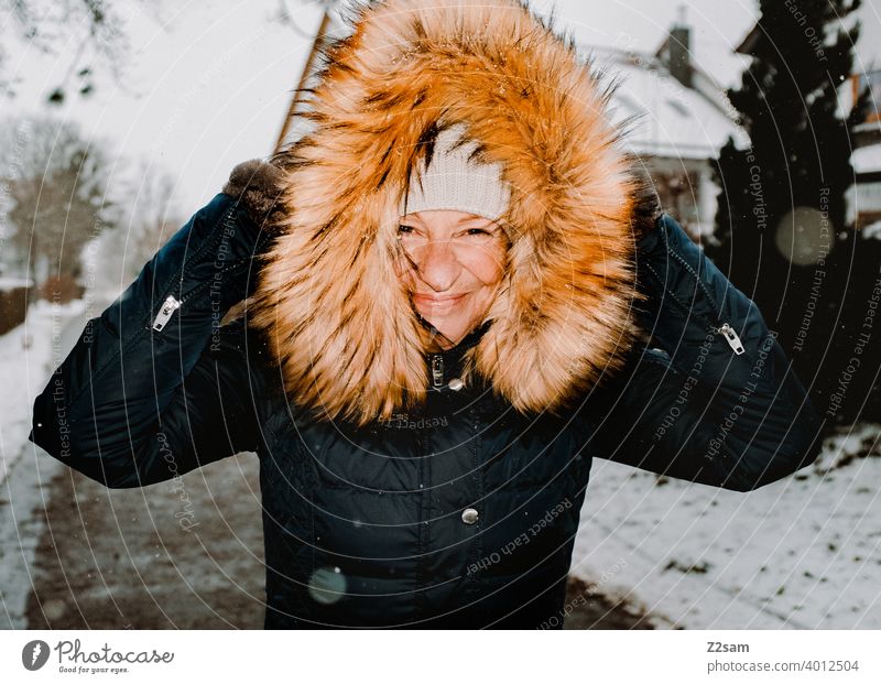 Frau spaziert bei Schneefall durch die Straßen spaziergang Spaziergang Winterspaziergang Kaminsims kunstpelz lachen lächeln Wärme schneefall Schafe Kälte weiss