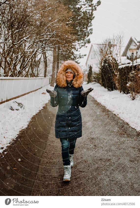 Frau spaziert bei Schneefall durch die Straßen spaziergang Spaziergang Winterspaziergang Kaminsims kunstpelz lachen lächeln Wärme schneefall Schafe Kälte weiss