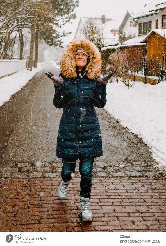 Frau spaziert bei Schneefall durch die Straßen spaziergang Spaziergang Winterspaziergang Kaminsims kunstpelz lachen lächeln Wärme schneefall Schafe Kälte weiss