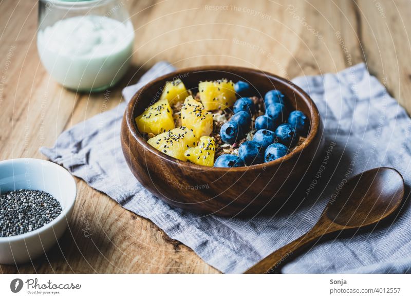 Müsli mit Heidelbeeren und Ananas in einer Holz Schüssel frisch Haferflocken Frühstück Gesunde Ernährung Getreide Bioprodukte Schalen & Schüsseln Nahaufnahme