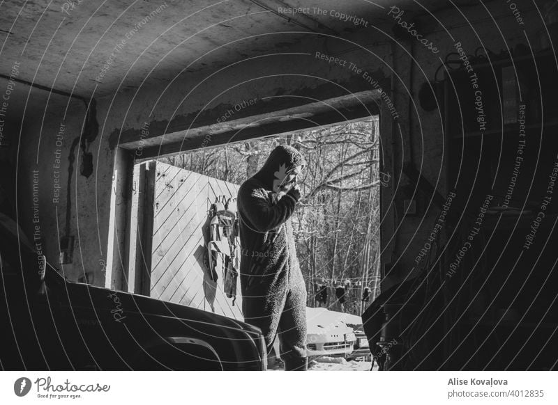 Sonntagsfaulheit Mann Person Tracht Rauchen Stehen Garage PKW Mann in einer Garage Blick aus der Tür Licht & Schatten Winter Garagentor Schwarz-Weiß-Fotografie