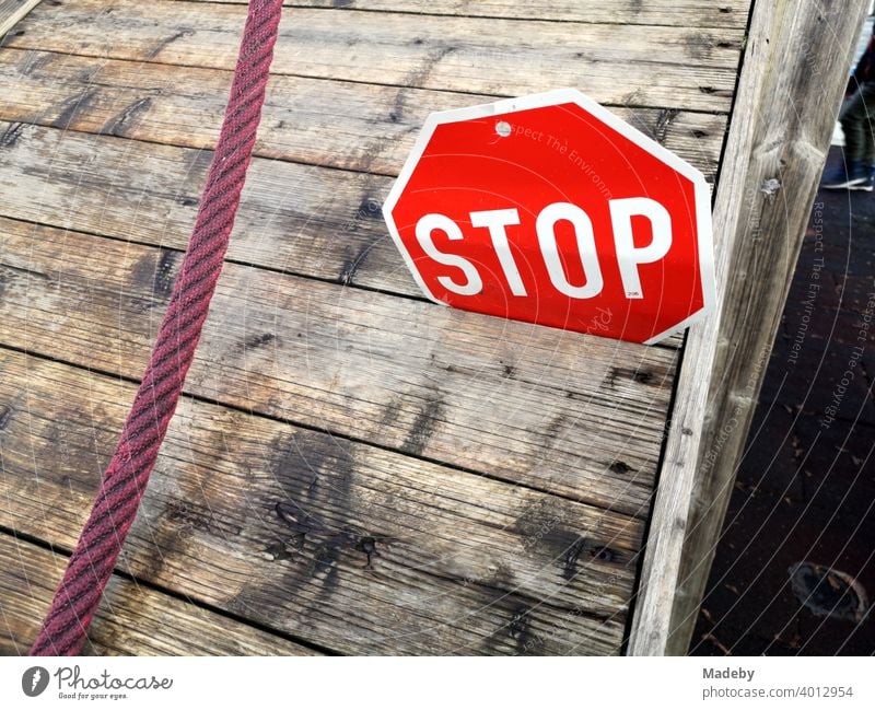 Stoppschild aus Blech in der Ritze einer Holzpritsche mit rotem Seil auf einem Kinderspielplatz an der Grundschule in Wettenberg Krofdorf-Gleiberg bei Gießen in Hessen