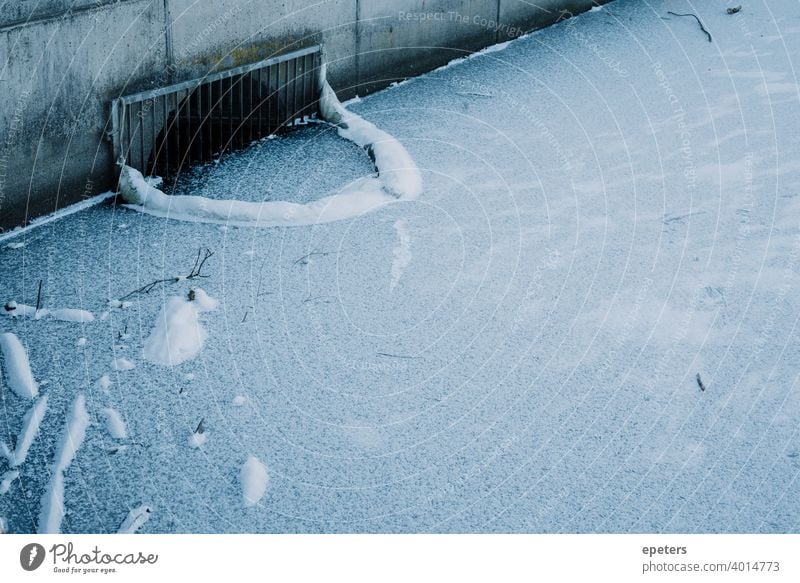 Abfluss an einem zugefrorenen See im Winter in Hamburg Steilshoop blau schatten Außenaufnahme Farbfoto Stadt Tag trist gefrorener See Appelhoffweiher Schnee