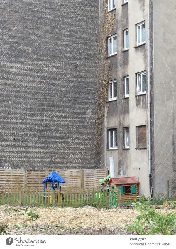 Spielplatz im Hinterhof Tristesse Kindheit Spielen Außenaufnahme Menschenleer Farbfoto Einsamkeit trist Zentralperspektive öde Traurigkeit Haus Zaun