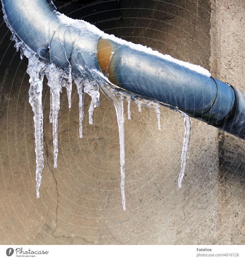 Eiszapfen an einer Regenrinne vor einer Hauswand Winter kalt gefroren Frost blau weiß Wasser frieren Außenaufnahme Farbfoto Menschenleer Tag Himmel Nahaufnahme