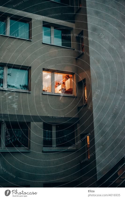 Fassade eines Wohnhauses am Abend, in einem Fenster brennt Licht. Fassadr Zuhause abends gemütlich wohnen mehrfamilienhaus Haus Mietshaus Licht an stimmungsvoll