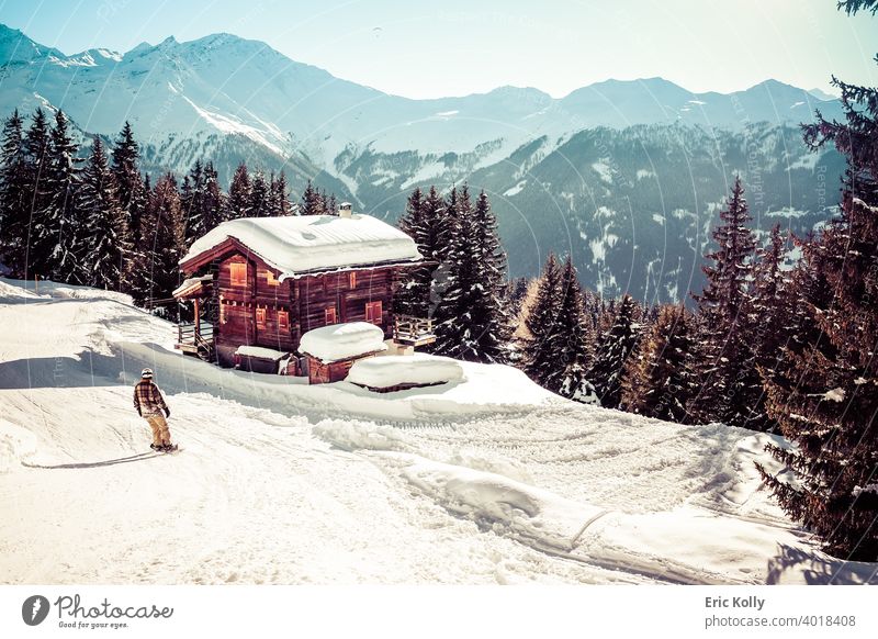 Skigebiet von Verbier mit einem Chalet mit Schnee bedeckt und ein Snowboarder im Vordergrund, aufgenommen in Verbier, Schweiz Winter kalt Außenaufnahme weiß