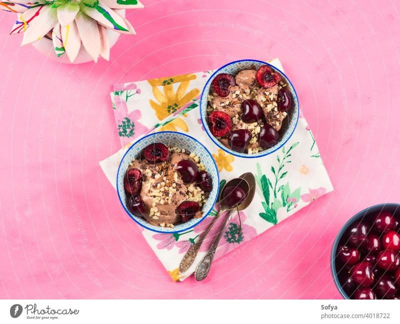 Schokoladeneis mit Streuseln, Nüssen und frischen Kirschen auf rosa Eis Sahne Eisbecher Vanille Dessert Glas Schalen & Schüsseln Lebensmittel Nut Baggerlöffel