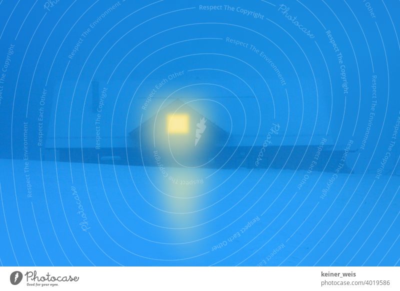 Ein Haus mit Licht im Fenster zeigt den Heimweg durch den kalten Winter. Blaue Stunde. blaue Stunde Schnee Nacht Dunkelheit verschneit Hütte gelb Farbkontrast