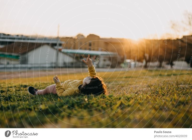 Nettes Mädchen zeigen auf den Himmel Kind 1-3 Jahre Gras Lügen Mensch Farbfoto Kleinkind Kindheit Außenaufnahme Tag Natur feminin träumen Punkt Porträt Spielen