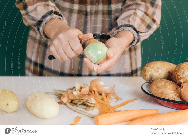 Frau schält in ihrer Küche auf weißem Marmor Zwiebeln ab, um ihr Essen zuzubereiten. sich[Akk] schälen Gemüse Kartoffeln Veganer heimwärts peel-off angeblättert