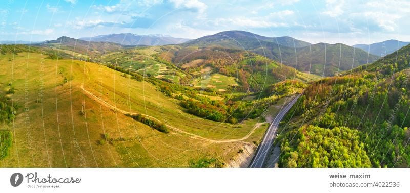 Landstraße in den Bergen. Abendliches Sonnenlicht auf Hügeln. Frühling grün ländlichen Landschaft. Straße Berge u. Gebirge Ansicht Panorama Antenne Serpentine