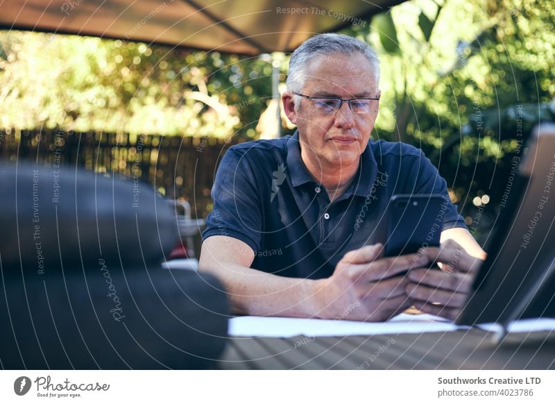 Kleingewerbetreibender arbeitet an einem Mobiltelefon mit Werkstatt im Hintergrund Kaukasier männlich Mann 60's Hobby Hobbyisten offen authentisch Menschen