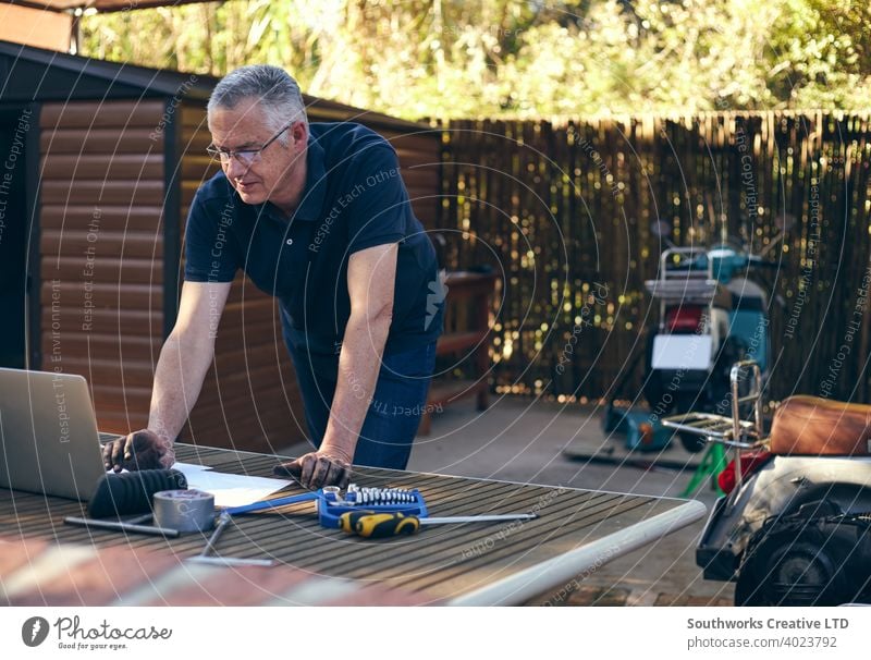 Kleiner lächelnder Geschäftsinhaber arbeitet am Laptop Kaukasier männlich Mann 60's Hobby Hobbyisten offen authentisch Menschen Heim-Hobbys Handwerk Person