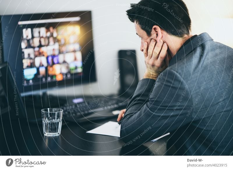 Mann arbeitet am Computer arbeiten Konferenz online Homeoffice Besprechung genervt erschöpft gelangweilt Schreibtisch