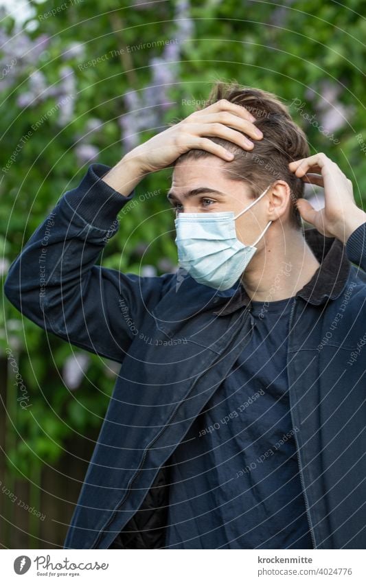 Jugendlicher mit Schutzmaske greift sich an die Stirn Teenager im Freien Sommer jung coronavirus covid-19 COVID Coronavirus Corona-Virus Gesundheit