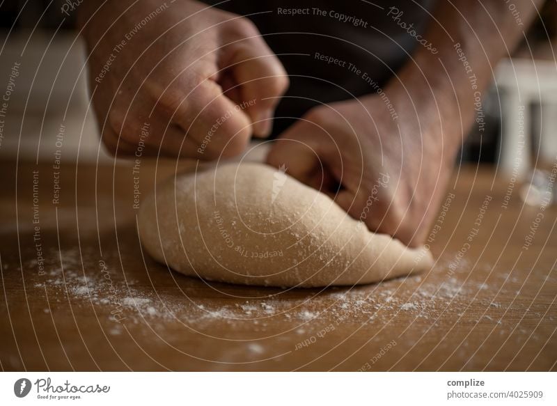 Ein Teig wird auf einem Küchentisch geknetet Teigwaren Pizzateig kneten Mehl einstauben selbstgemacht backen Bäckerei Backwaren Brot Brotteig Hände Faust Kind