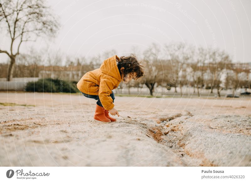 Seitenansicht eines Kindes mit roten Gummistiefeln beim Spielen im Freien Kindheit Freude Kindheitserinnerung Kleinkind Junge Fröhlichkeit Farbfoto Mensch