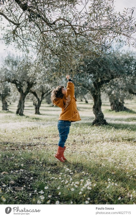 Kind mit roten Gummistiefeln spielt mit Baum Umwelt Natur Kindheit Frühling Mädchen Tag grün Farbfoto Außenaufnahme authentisch heiter Freude Pflanze jung Glück