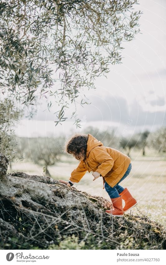 Kind mit roten Gummistiefeln kletternd Klettern im Freien Natur Frühling erkunden Abenteuer Außenaufnahme Spielen Mensch Regen Kindheit Freude Stiefel